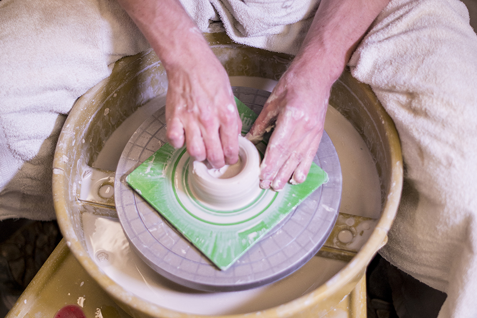 Hands shaping clay on a pottery wheel