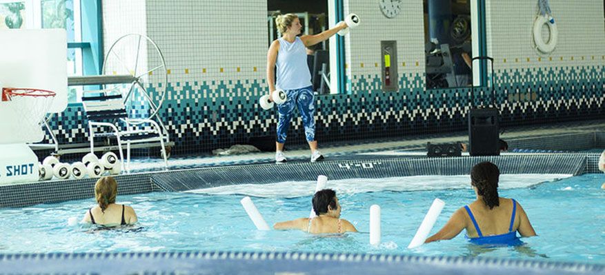 an female instructor teaches a water aerobics class